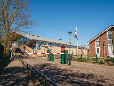 a school building with a fence in front of it at Holiday Home Campi 400 by Interhome in Uitgeest