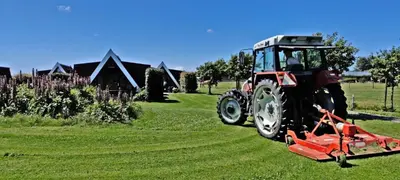 a red tractor is parked on a field at Hotelhuisje Warmenhuizen #B in Warmenhuizen