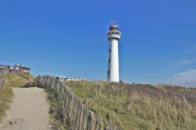 a lighthouse on top of a hill with a fence at Hotelhuisje Warmenhuizen #B in Warmenhuizen