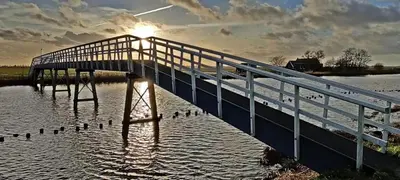 a bridge over a body of water with ducks on it at Hotelhuisje Warmenhuizen #C in Warmenhuizen