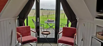a room with two chairs and a table with a view of a field at Hotelhuisje Warmenhuizen #C in Warmenhuizen