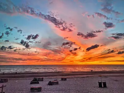 a sunset on a beach with chairs and the ocean at Garden find zandvoort in Bentveld