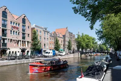 a red boat on a river in a city at RedLight District Smokers Friendly Private Studio in Amsterdam
