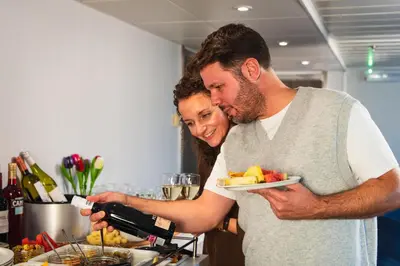 a man holding a wine bottle and a woman holding a plate of food at DFDS Mini Cruise Amsterdam - Newcastle - Amsterdam in IJmuiden