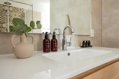 a bathroom sink with a vase with wine bottles on it at Relaxen aan de kust by Droomvilla in Sint Maarten