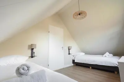 a attic bedroom with two beds and a mirror at Slapen aan zee by Droomvilla in Sint Maarten