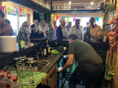 a group of people standing in a kitchen with a bartender at Chalet 2a op Recreatiepark De Wielen in Sint Maarten