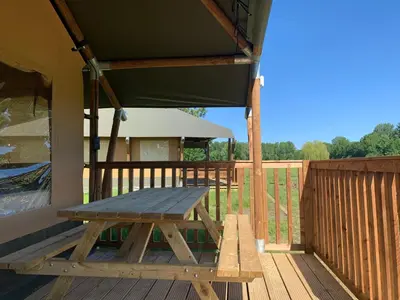 a picnic table on the deck of a house at Glamping lodge with Eco-Wellness in Zeewolde