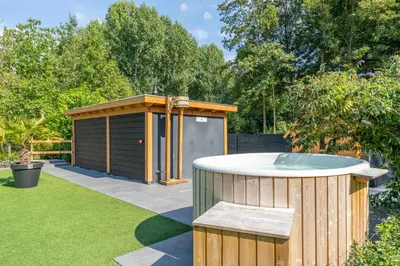 a hot tub in a garden with a shed at Glamping lodge with Eco-Wellness in Zeewolde
