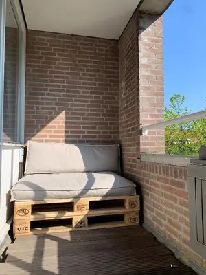 a bed sitting on a porch with a brick wall at Lovely City Center Apartment in Alkmaar