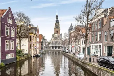 a canal in a city with a clock tower at Lovely City Center Apartment in Alkmaar