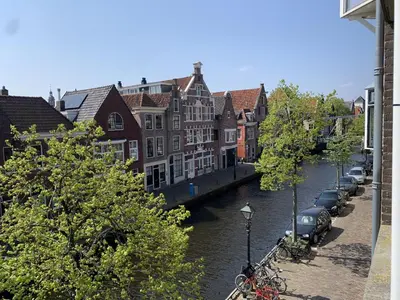 a river with buildings and cars parked next to a canal at Lovely City Center Apartment in Alkmaar