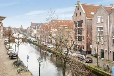 a river in a city with parked cars and buildings at Lovely City Center Apartment in Alkmaar