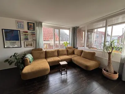 a living room with a couch and two windows at Lovely City Center Apartment in Alkmaar