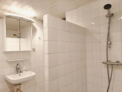 a white tiled bathroom with a shower and a sink at Lovely City Center Apartment in Alkmaar