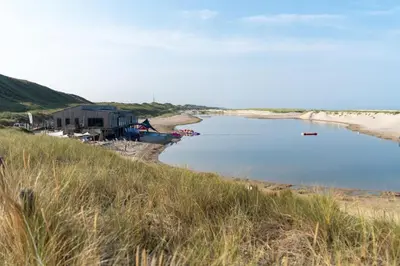 a beach with a house and a body of water at Park Heerehof in Schoorl