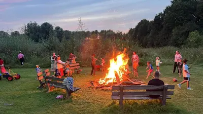a group of people around a fire in a field at Green Tiny House with shared pool in Zeewolde