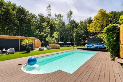a swimming pool in a backyard with a wooden deck at Green Tiny House with shared pool in Zeewolde