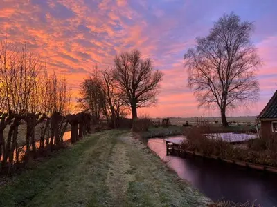 a sunset over a river with trees in a field at B&B De Beijersche Stee, Logies aan de Waterkant in Stolwijk