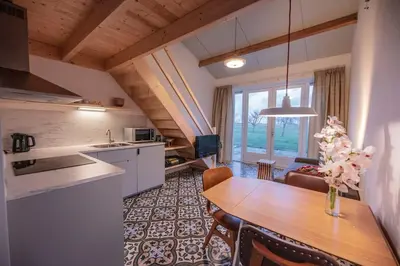 a kitchen and dining room with a table and a kitchen and a living room at 't Winkeltje - Vakantiehuisje op boerderij Huize Blokland in Hem