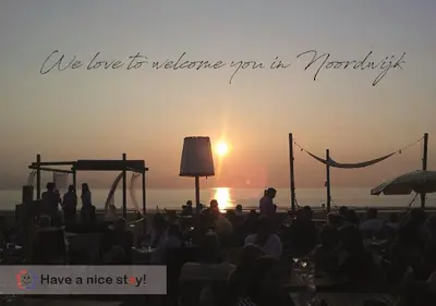a group of people watching the sunset on a beach at Have a nice stay! - North Sea Home in Noordwijk aan Zee